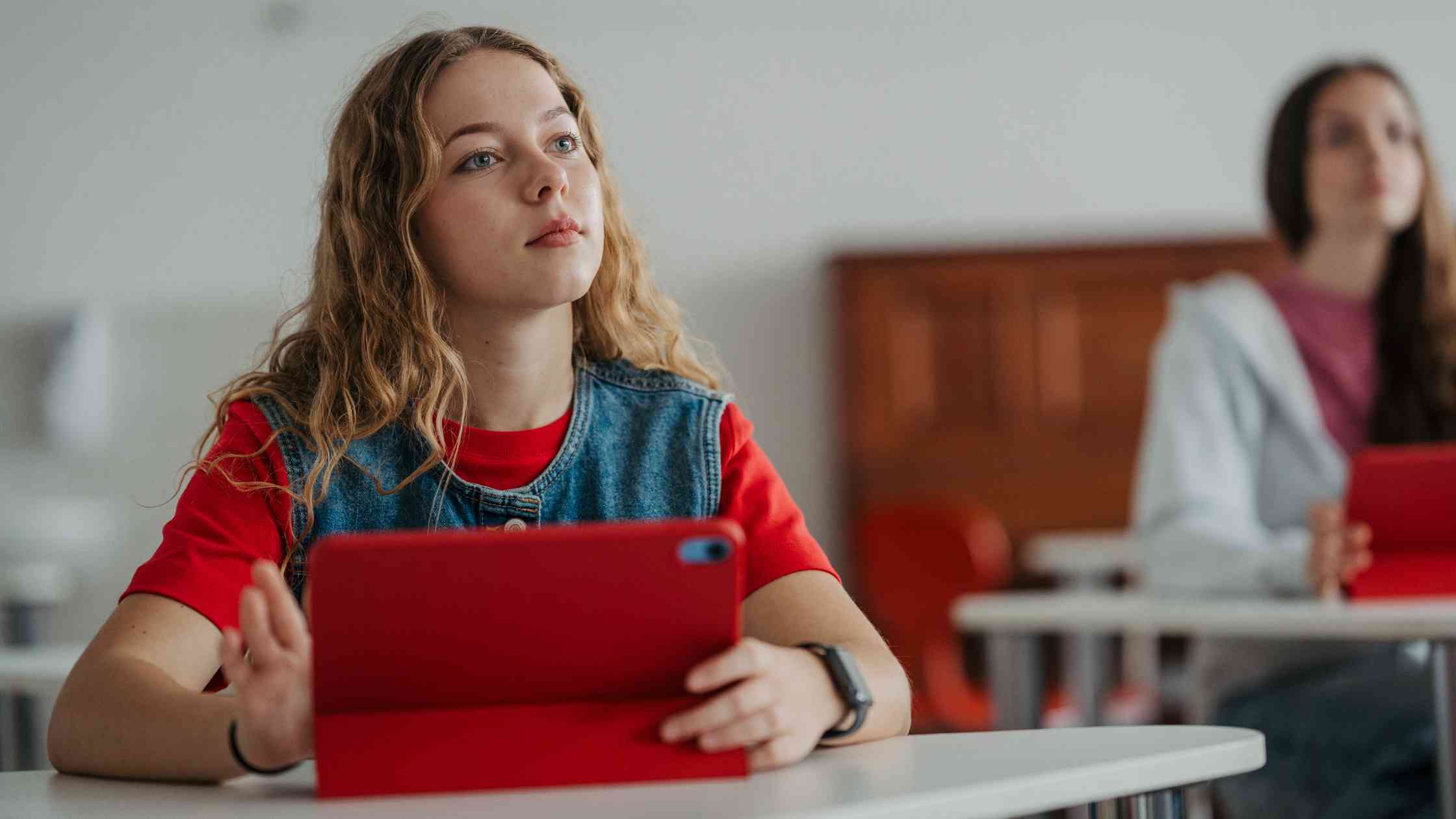 A student holding a tablet in a class, representing planning next steps after a 1280 PSAT score and preparing for the SAT.